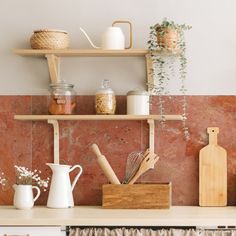 a kitchen shelf with utensils and other items on it in front of a marble wall