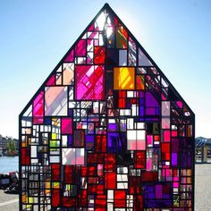 a house made out of stained glass in a parking lot with the sun shining behind it