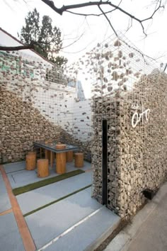 a building made out of stacked rocks with graffiti on the front and side walls that read,