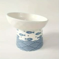 a white and blue bowl with fish on the bottom is sitting in front of a white background