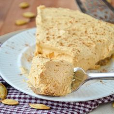 a piece of cake on a plate with a fork and some pistachios