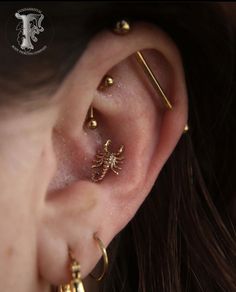 a close up of a person wearing gold colored ear piercings with bee design on them