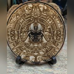 a wooden plate with an image of darth vader in the center and symbols on it