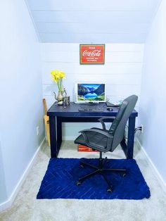 a desk with a chair and laptop on it in a room that has white walls