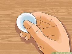 a hand holding a white object on top of a wooden table with wood planks