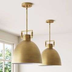 two brass pendant lights hanging from the ceiling in a room with white walls and windows