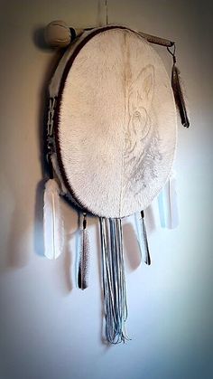 a white clock with feathers hanging from it's face and two pendulums on the wall