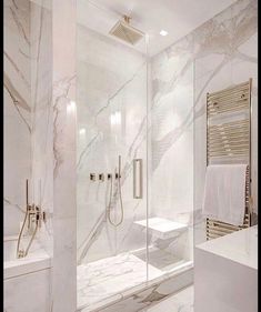 a bathroom with marble walls and flooring, including a walk in shower next to a white bathtub