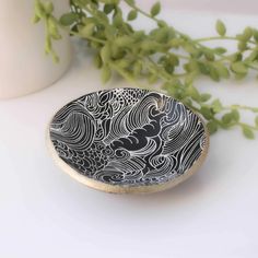 a black and white plate sitting on top of a table next to a vase filled with flowers