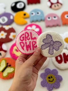 someone is holding up some buttons with the word girlie on them in different colors