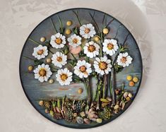 a plate with flowers painted on it sitting on a wall next to a planter