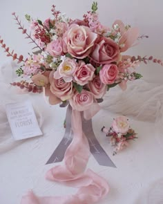 a bouquet of pink flowers sitting on top of a white table next to a card