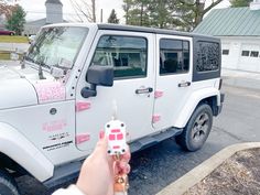 a person holding a car key in front of a white jeep parked on the street