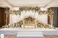 an elegant wedding setup with flowers and greenery on the wall, along with a couch