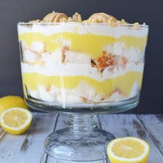 a lemon trifle in a glass dish with sliced lemons around the edges and on top