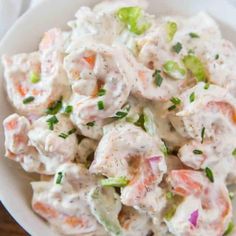 a white bowl filled with chicken salad on top of a table