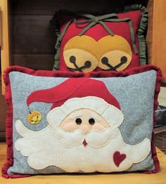 two pillows with santa claus on them sitting next to each other in front of a bookcase