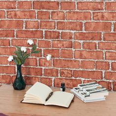 an open book sitting on top of a wooden table next to a vase with flowers