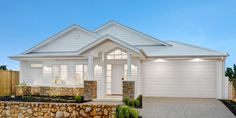 a white house with a stone wall in the front yard