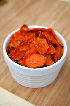 a white bowl filled with sliced carrots on top of a wooden table