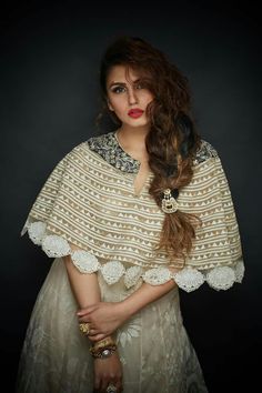 a woman with long hair wearing a white dress and a shawl over her shoulders