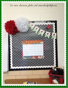 a black and white polka dot bulletin board with red pom poms on it