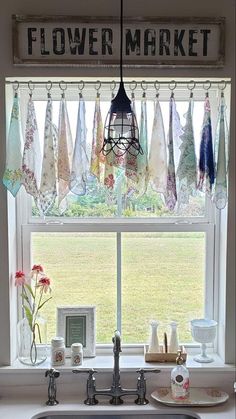 a kitchen sink under a window with towels hanging from it's rod and the words flower market above it