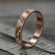 a wedding band that is sitting on top of a piece of measuring tape with an engraving pattern