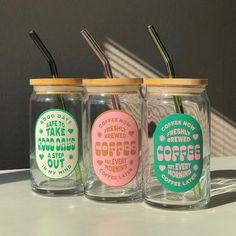 three glass jars filled with different types of coffee and straws on top of a table