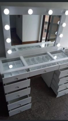 a white vanity with lighted drawers and lights on it's sides, in front of a window