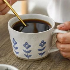 a person holding a spoon over a cup of coffee