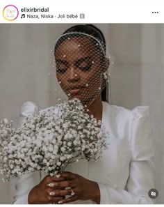 a woman wearing a veil holding a bouquet of flowers