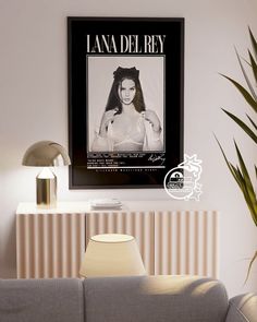 a living room with a gray couch and a poster on the wall above it that says lana del ray