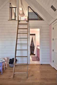 a ladder is in the middle of a room with white walls and wood flooring