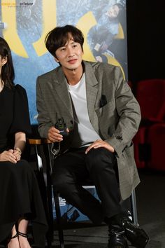 two people sitting next to each other in front of a movie poster on the wall