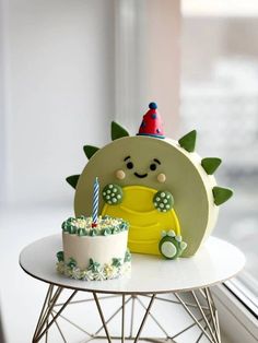 a birthday cake sitting on top of a white table next to a small dinosaur figure