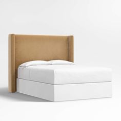 an upholstered bed frame with white sheets and pillows on the headboard is shown in front of a plain background