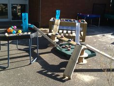 two children's play sets with balls and ladders on the ground in front of a building