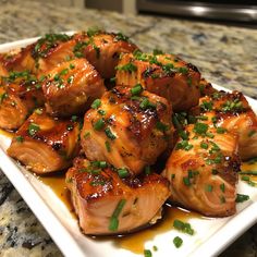 a white plate topped with meat covered in sauce and garnished with scallions