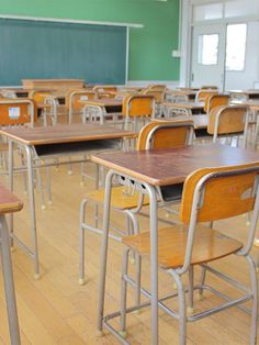 an empty classroom with wooden desks and chairs