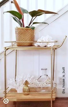 a potted plant sitting on top of a gold shelf next to a stair case