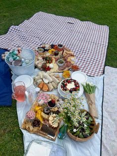 a picnic table with food and drinks on it in the middle of a grassy area