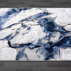 a blue and white area rug with an abstract design on the floor in front of a wooden floor