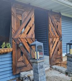 a couple of wooden doors sitting on the side of a blue house next to a fire hydrant