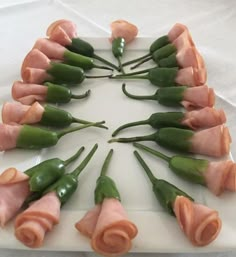 a white plate topped with green beans and ham wrapped in rolled up flowers on top of each other