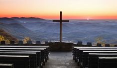 an empty church with the sun setting in the background and mountains to the side,