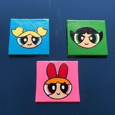 three square paintings with cartoon faces painted on them