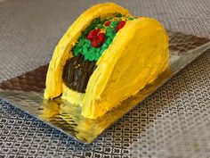 a taco cake sitting on top of a metal plate covered in frosting and decorations