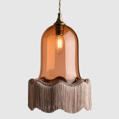 a light fixture with fringes hanging from it's side and an orange glass shade