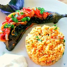 a white plate topped with fish and rice next to a side of sour cream sauce